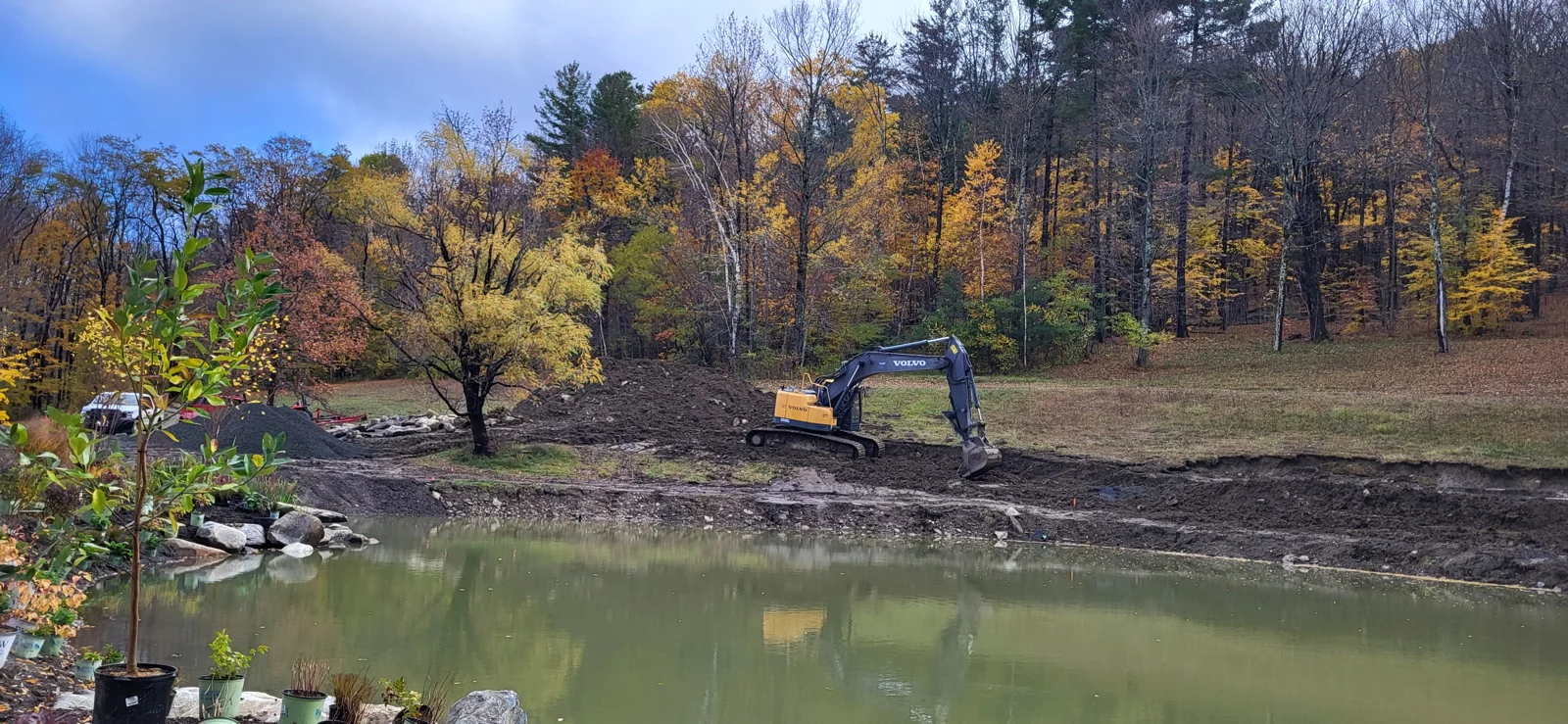 Large tracked excavator working along the pond bank during restoration