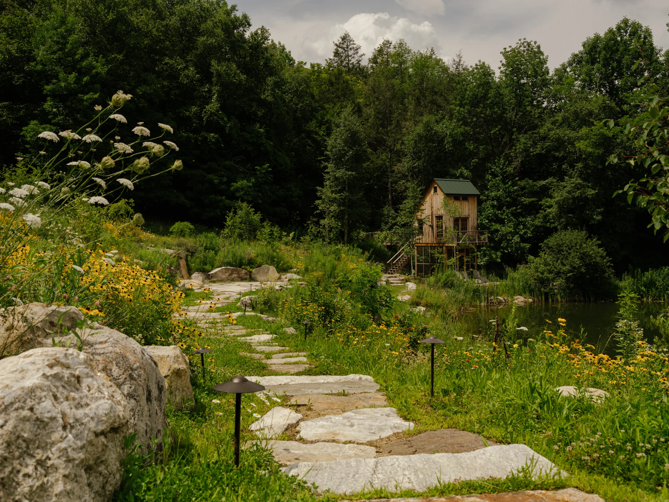 An informal stone path winds through pond-side planting.