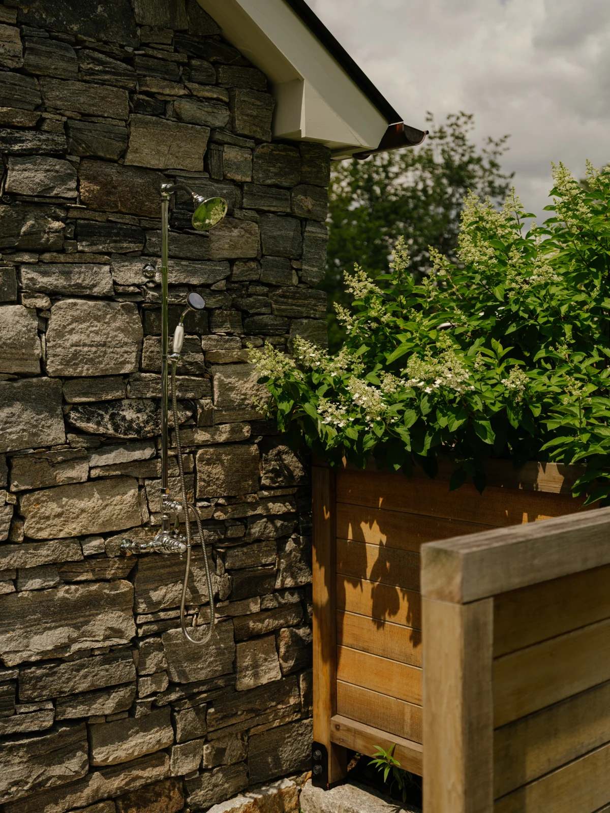 An outdoor shower framed by stone walls and timber screens.