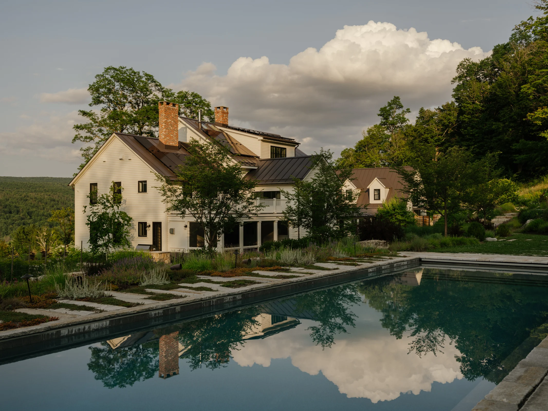 Natural stone pool terrace surrounded by richly planted gardens at Morningside